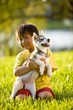 Young Asian boy holding Alaskan Klee Kai puppy sitting on grass