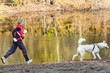 The sports woman with a dog run along coast of the rivers